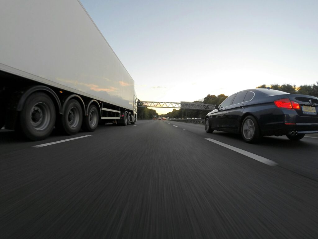 pexels-photo-192364-192364 Cars and a truck speed along a highway under the clear sky, showcasing transportation dynamics.